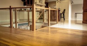 Room divided by wood flooring and tiles in kitchen.