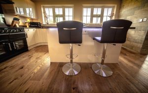 Wooden Floor in a kitchen. Two stool chairs sit at an island in front of the camera