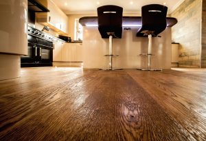 Wooden Floor in a kitchen. Two stool chairs sit at an island in front of the camera - low angle