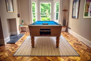 Pool Table on a rug over zigzagged wooden flooring