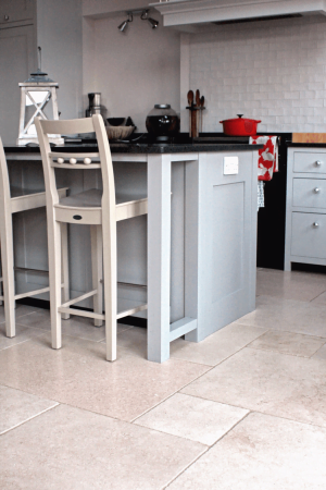 Tiled kitchen with grey cupboards and tall chairs.