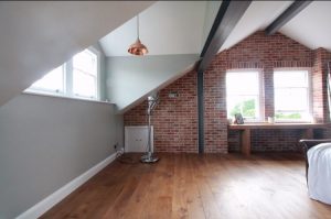 Spacious Attic, hardwood flooring again large red brick wall