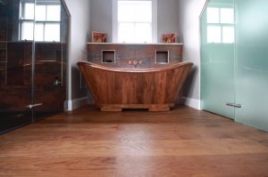 Copper bath on brown red wood flooring